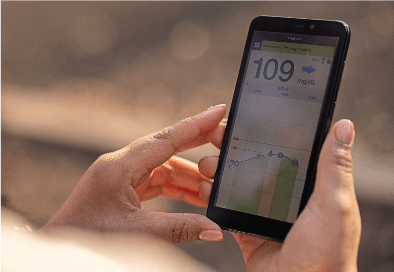Hands hold a smartphone displaying the Eversense glucose monitoring app reading 109 mg/dL.
